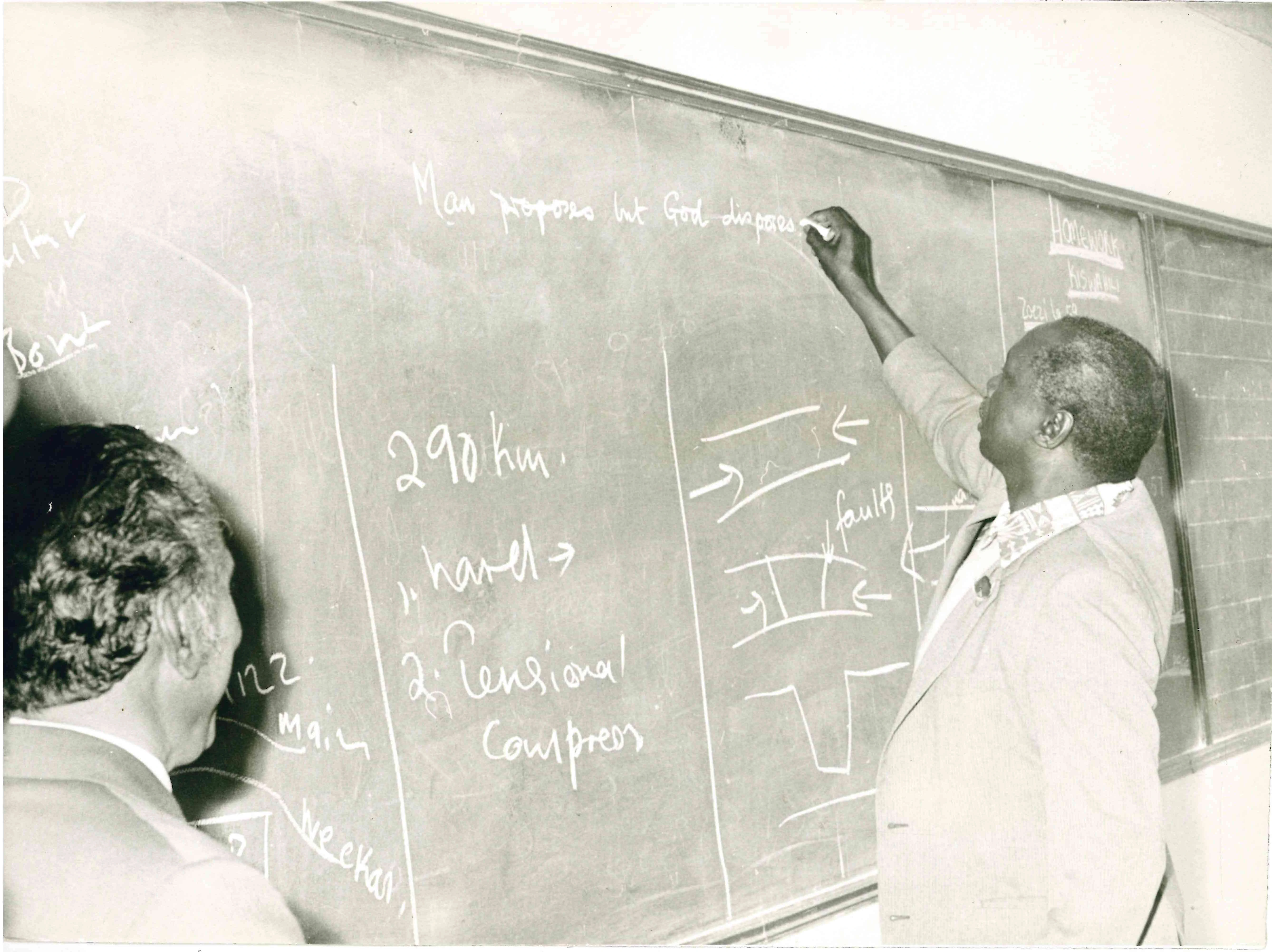 President Daniel Arap Moi trying his teaching writing skills on the blackboard at Moi Equator Girls High School Nanyuki during a visit to the school