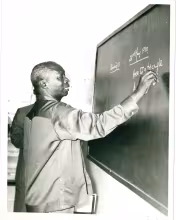 President Daniel Arap Moi a former teacher practices his skills on a black board during a school visit in Nakuru